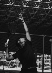 Male tennis player serving the tennis ball into play.
