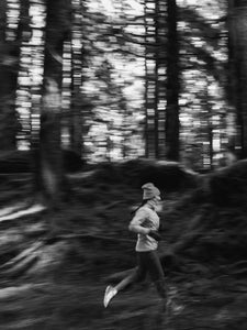 Woman running through the woods in cold weather.